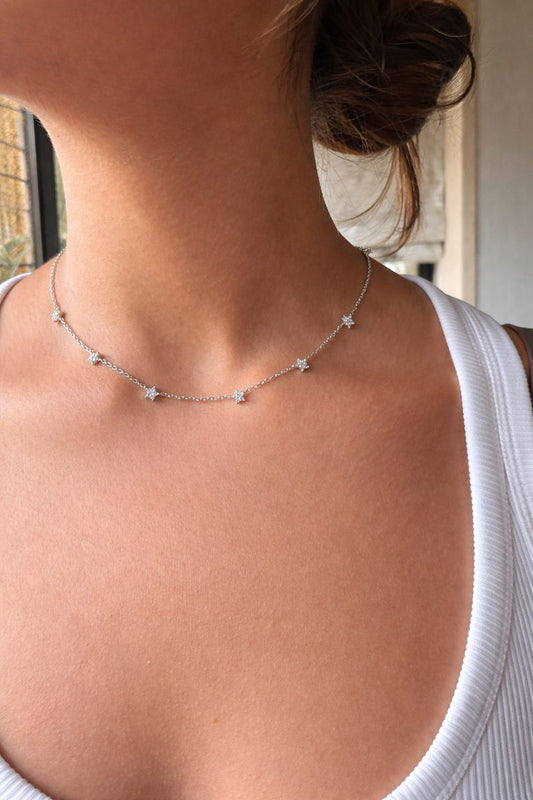Necklace with star-shaped pendants on a person wearing a white top.
