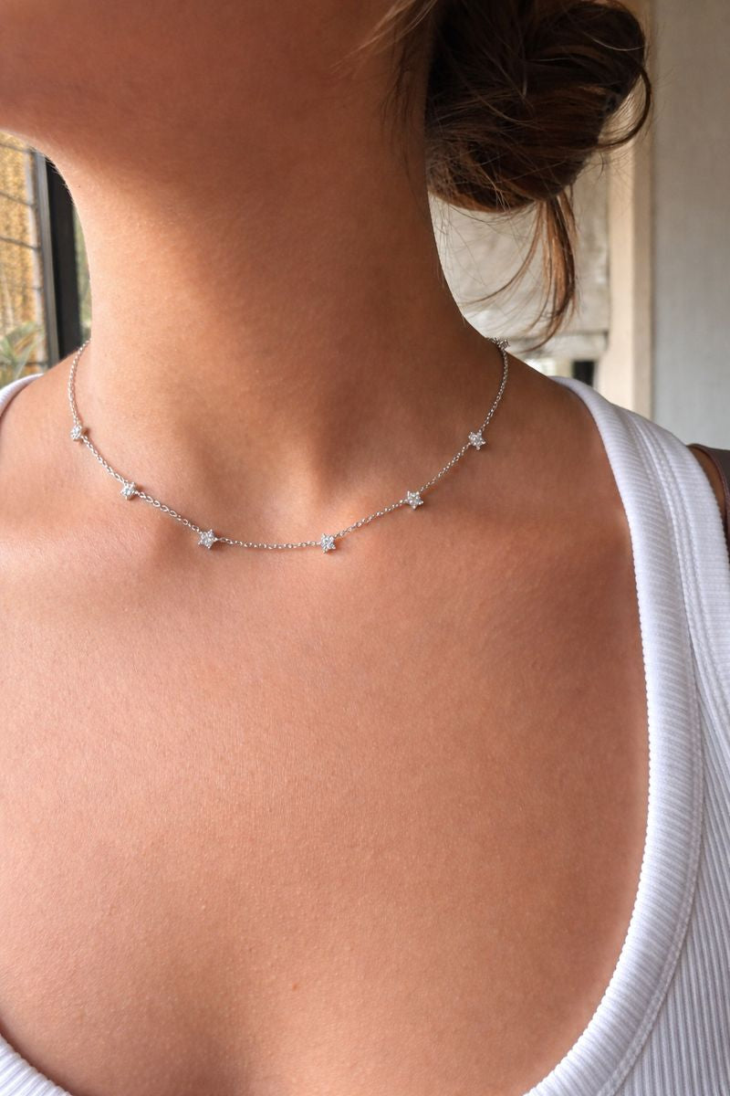 Necklace with star-shaped pendants on a person wearing a white top.