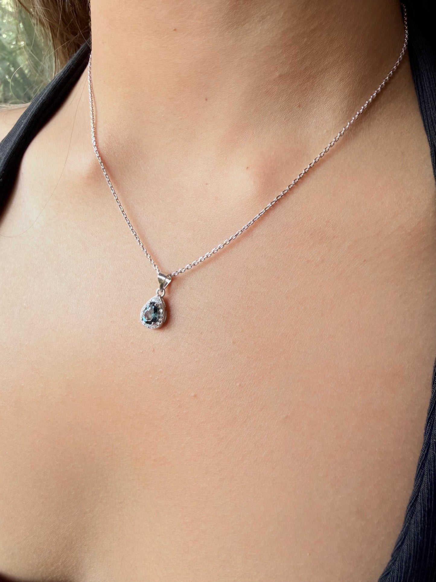 Necklace with a pendant worn by a person, with a blurred natural background